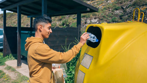 Young man throwing plastic garbage to container