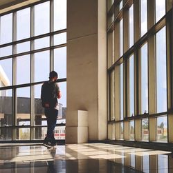 Rear view of man standing by window in building