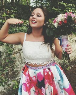 Portrait of smiling woman standing against bouquet