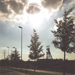 Low angle view of trees against cloudy sky