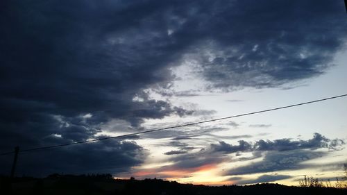 Silhouette of power lines against cloudy sky