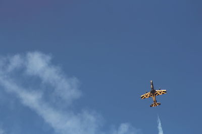 Low angle view of airplane flying against blue sky