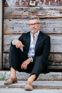 Portrait of businessman sitting against wooden wall