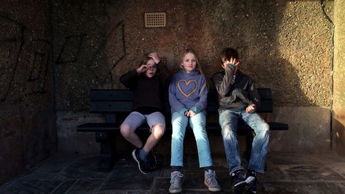 Portrait of young couple sitting on wall