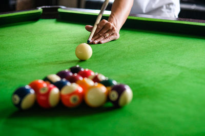 Cropped hand of man playing pool ball