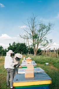 Rear view of man with woman standing by plants against sky