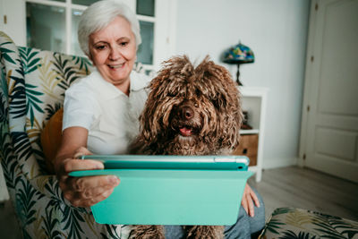 Senior woman with dog using digital tablet