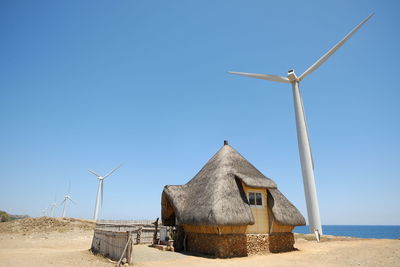 Traditional windmill on land against clear sky