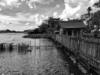 Wooden house by lake and building against sky