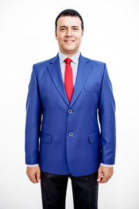 Portrait of confident smiling businessman wearing suit standing against white background