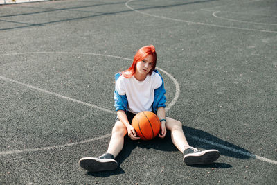 A charming teenage girl with a basketball is resting after a workout. a girl on the sports field.