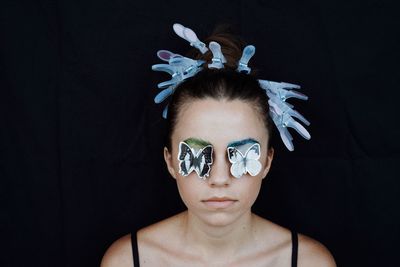 Close-up of woman with artificial butterflies against black background