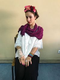 Portrait of beautiful young woman standing against wall