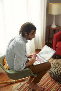 High angle view of man looking away while using laptop computer at home