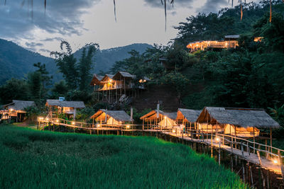 Houses on field by buildings against sky at dusk