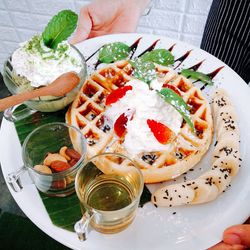 Cropped hand holding food and drink in plate