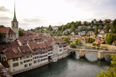 Arch bridge over river amidst buildings in city