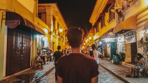 Rear view of people standing on street at night