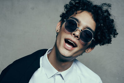 Portrait of young man wearing sunglasses against wall