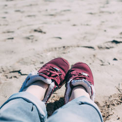 Low section of woman wearing shoes on beach