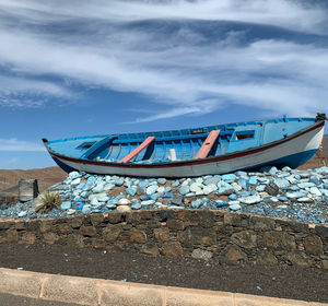 Fishing boat moored on beach against sky