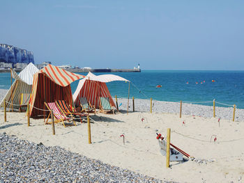 Deck chairs on beach against clear sky