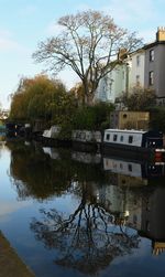 Canal by buildings in city against sky