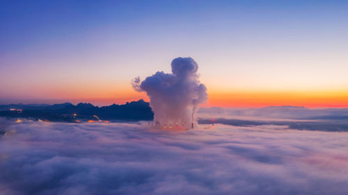 Factory emitting smoke against sky during sunset