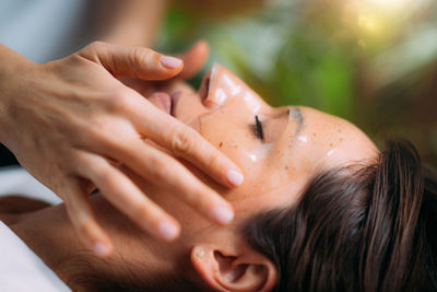 Beautician putting beauty face mask on womans face