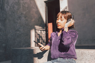 Girl looking away while sitting on wall