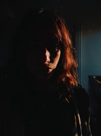 Close-up portrait of young woman in dark room