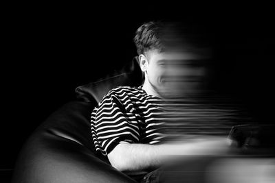 Portrait of boy sitting against black background