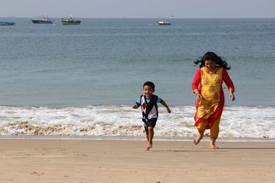 Mother and son running on shore at beach