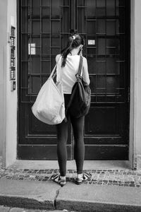 Rear view of woman walking on street against building