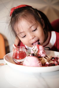 Portrait of kid with strawberry ice cream on table