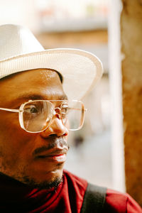 Determined african american male wearing elegant hat and clothes standing in street looking away