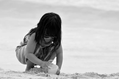 Full length of girl playing with sand at beach