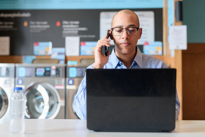 Young man using mobile phone on table