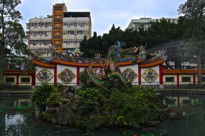 Dragon statue amidst pond against temple