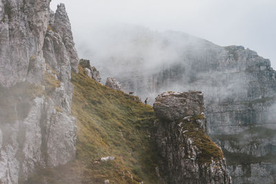 Scenic view of foggy rocky mountains against sky with wild animals