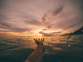 Shadow of hand on sea during sunset