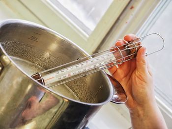 Cropped hand holding thermometer in stew pot