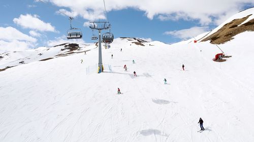 People skiing on snowcapped mountain against sky