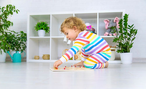 Portrait of boy playing with toy on hardwood floor at home