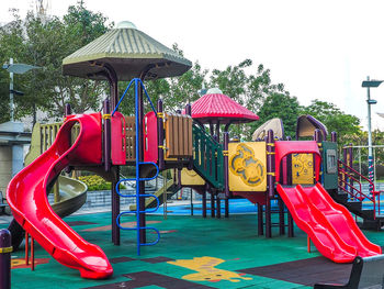 Empty chairs in playground against trees in park