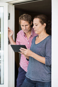 Couple using digital tablet at doorway