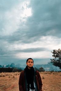 Portrait of smiling man standing on field against sky