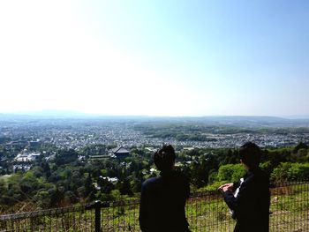 Rear view of man looking at cityscape against sky