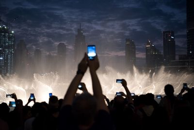 People photographing at music concert against sky