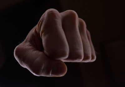 Cropped hand punching against black background